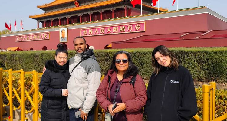Los viajeros posan frente a la Puerta de Tiananmen decorada con banderas rojas y el retrato de Mao en Beijing.