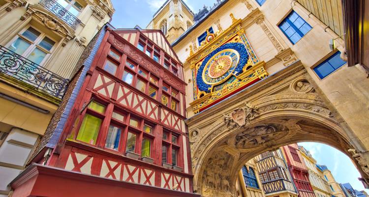 Vue rapprochée ascendante de l'arche de l'horloge Gros-Horloge de Rouen et des maisons à colombages avec des touristes marchant en dessous