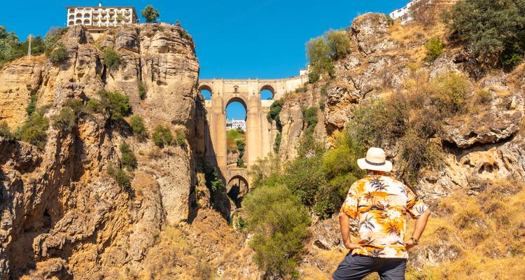 Man admiring the dramatic Puente Nuevo bridge spanning a deep gorge in Ronda