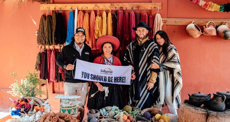 Démonstration de tissage avec des habitants et des visiteurs tenant une bannière à l'intérieur d'un atelier textile coloré.