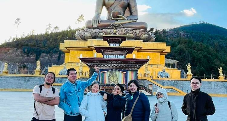 Des visiteurs prenant la pose devant la colossale statue de Bouddha Dordenma par une journée ensoleillée.