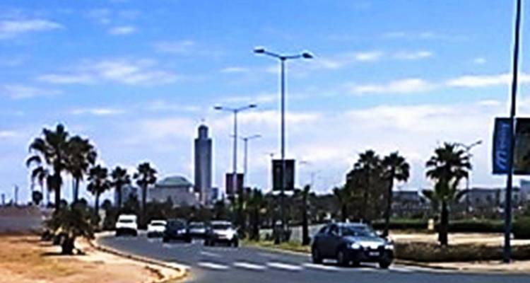 Uitzicht in de verte op de toren van de Hassan II-moskee tijdens een rit langs de weg met palmbomen