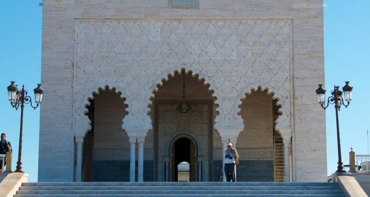 Bezoeker staand op trappen onder sierlijke bogen van het koninklijke mausoleum complex