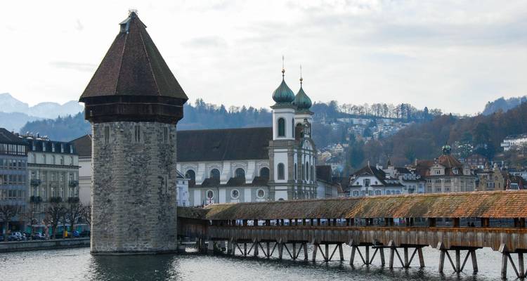 Le pont de la Chapelle et la tour de l'eau de Lucerne enjambent la rivière Reuss avec des clochers d'église baroques en arrière-plan.