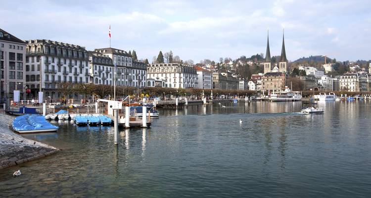 La promenade au bord du lac de Lucerne présente des bâtiments historiques, des clochers jumeaux et de petites embarcations.
