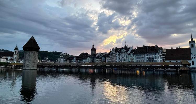 Vue répétée du pont en bois de Lucerne au crépuscule avec des nuages dramatiques au-dessus.