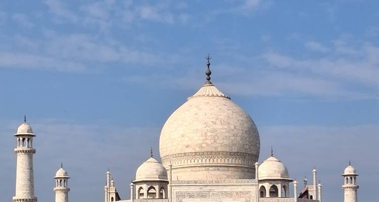 Une vue rapprochée met en évidence le dôme central et les minarets du Taj Mahal sur un ciel bleu parsemé de nuages.