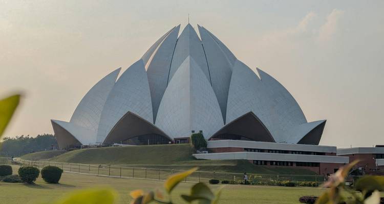 Les pétales blancs en forme de lotus du Temple du Lotus de Delhi s'étalent au-dessus de pelouses bien entretenues sous une douce lumière d'après-midi.
