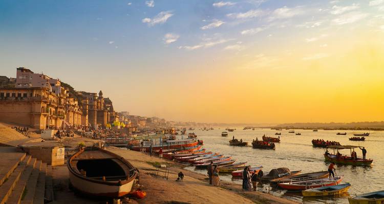 Les bateaux s'alignent le long des ghâts de Varanasi sur le Gange au coucher du soleil, tandis que la lumière dorée inonde la ville ancienne.