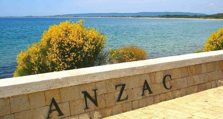 Stone seawall inscribed with 'ANZAC' overlooking the calm turquoise water of Gallipoli.