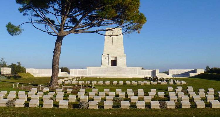 Lone Pine memorial tower rises above rows of neatly arranged headstones under a clear sky.
