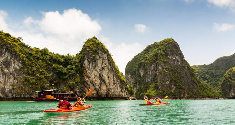 Los kayakistas reman en aguas turquesas entre imponentes karsts de piedra caliza en la Bahía de Ha Long