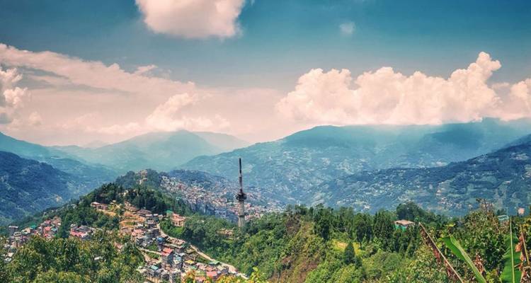 Vaste vallée de montagne avec des villages éparpillés sous un ciel rempli de nuages cotonneux