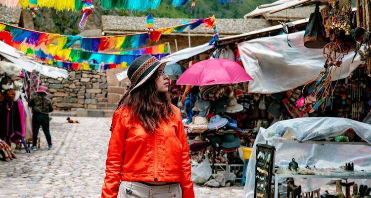Marché artisanal coloré avec textiles suspendus et objets d'artisanat où une femme en veste vive explore les étals.