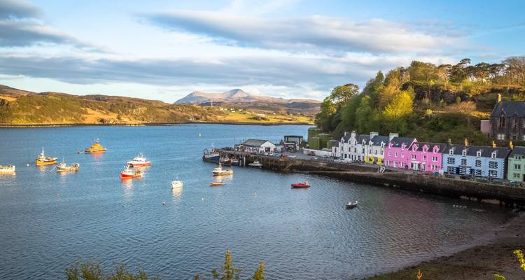 Ville portuaire colorée de Portree avec des bateaux de pêche ancrés dans une baie calme.
