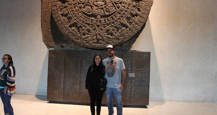 Paar posiert vor dem aztekischen Sonnenstein in einer Museumshalle