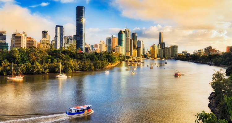 Amplia escena del río con ferry y el horizonte del distrito central de Brisbane bajo la cálida luz de la tarde