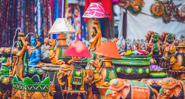 Étal de marché d'artisanat coloré présentant des statues de chameaux peintes et des lampes vives en Inde.