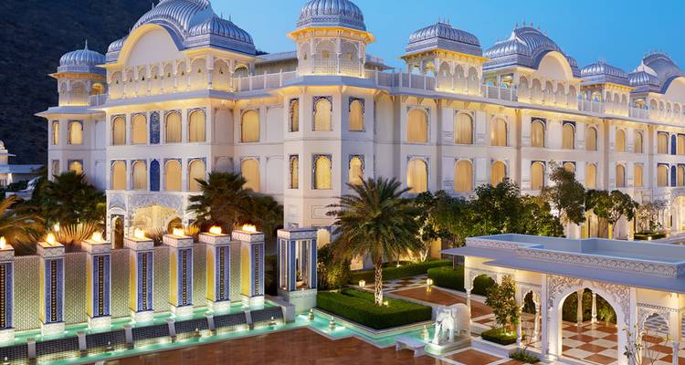 Illumination nocturne d'un grand hôtel palace avec dômes, fontaines et statues d'éléphants à Jaipur.