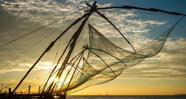 Silhouettierte chinesische Fischernetze fangen den goldenen Sonnenuntergang über dem Arabischen Meer ein.