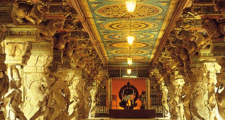 Couloir orné de piliers avec plafond peint coloré et éclairage chaleureux à l'intérieur d'un temple du sud de l'Inde.