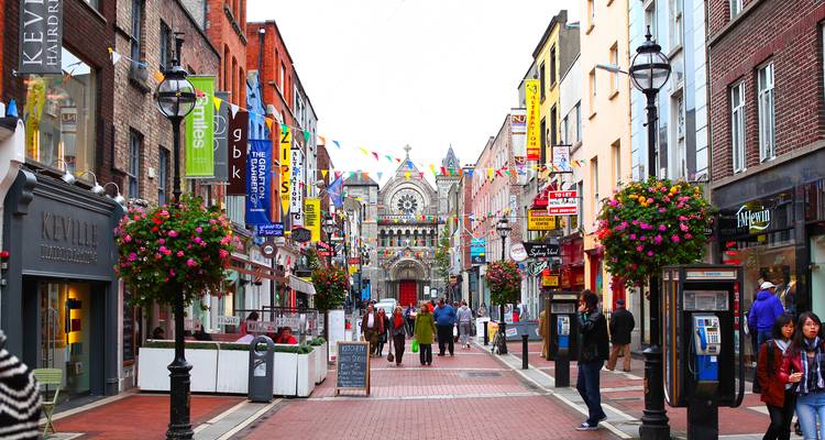 Bustling pedestrian shopping street in Dublin lined with colorful flags and storefronts
