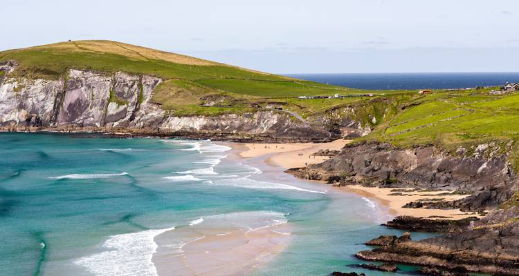 Turquoise waters and golden beach curving along green cliffs of the Dingle Peninsula