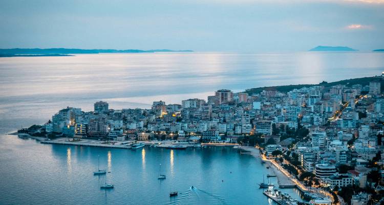 Evening skyline of a coastal city with a calm bay reflecting blue twilight