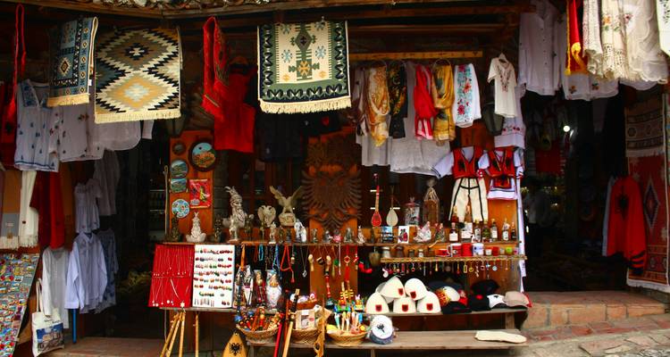 Colorful artisan stall displaying textiles, costumes, and souvenirs in a traditional bazaar alley