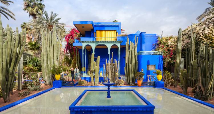 Villa bleue audacieuse et jardin de cactus du Jardin Majorelle avec des visiteurs admirant la piscine.