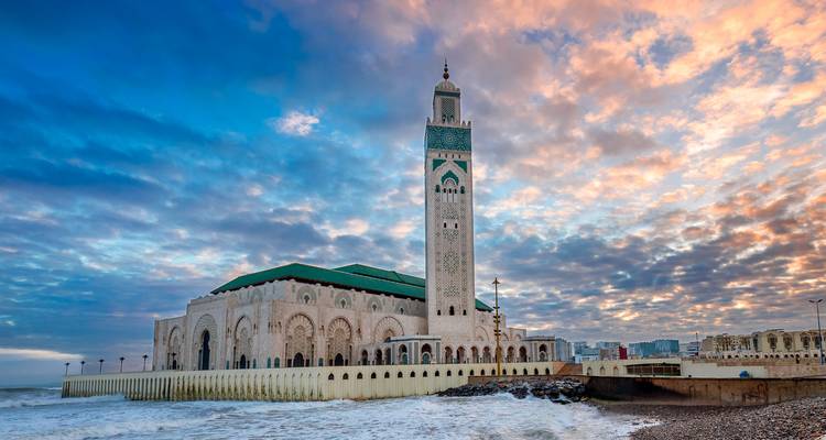 La majestueuse Mosquée Hassan II dominant les vagues de l'Atlantique sous un ciel dramatique au coucher du soleil à Casablanca.