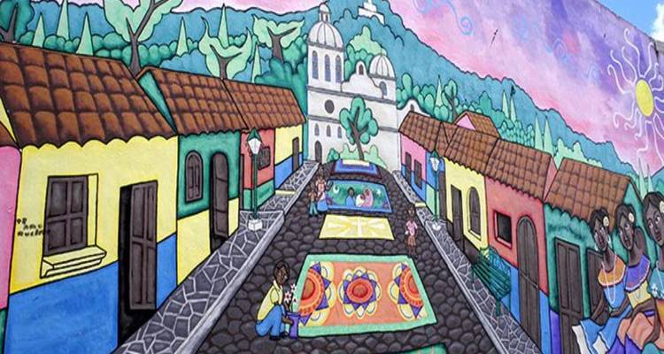 Mural de arte popular brillante que representa una calle de pueblo con una catedral y un telón de fondo montañoso.
