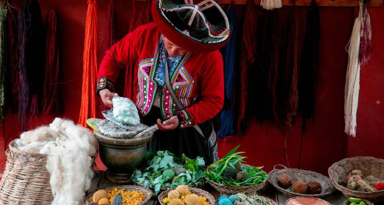 Artisan démontrant la préparation de teintures naturelles entouré de paniers de laine colorée et de plantes