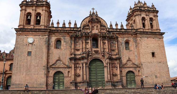 Fachada frontal de la Catedral de Cusco con ornamentada cantería barroca y torres gemelas de campanario contra un cielo brillante