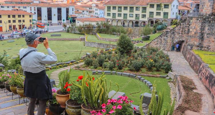 Viajero fotografiando jardines de terrazas coloridas y edificios coloniales junto a Qorikancha
