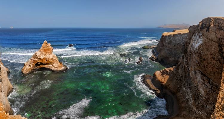 Dramatic cliffs and turquoise waves crash against the rugged shoreline of Paracas National Reserve.