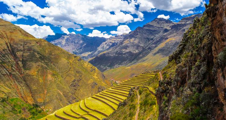 Ancient Inca agricultural terraces cascade down a valley surrounded by high Andean peaks.