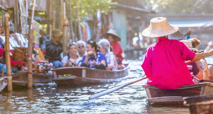 Mercado flotante bullicioso con vendedores y turistas en botes de madera a lo largo de un canal estrecho.