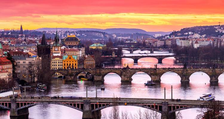 Coucher de soleil éclatant sur Prague avec le pont Charles et plusieurs ponts historiques enjambant la rivière Vltava.