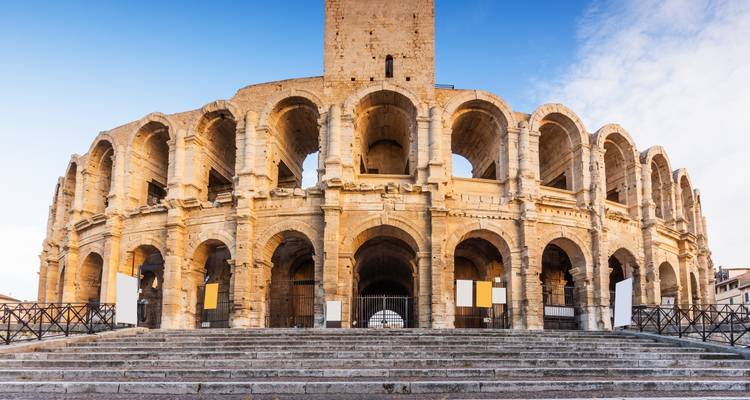 Impressionnant amphithéâtre romain d'Arles éclairé par une lumière chaude avec un ciel bleu en arrière-plan.