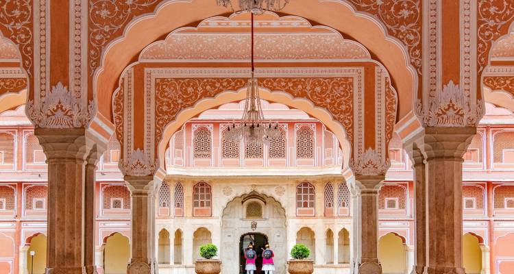 Kunstvoll verzierte Torbögen im Stadtpalast von Jaipur mit zwei Touristen, die das Interieur bewundern
