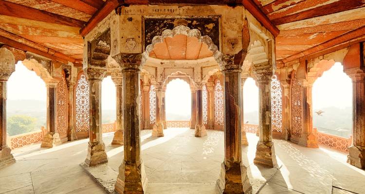 Sonnenbeschienener Innenpavillon des Amber Forts mit symmetrischen Säulen und vergitterten Fenstern, die sich zu hellen Ausblicken öffnen