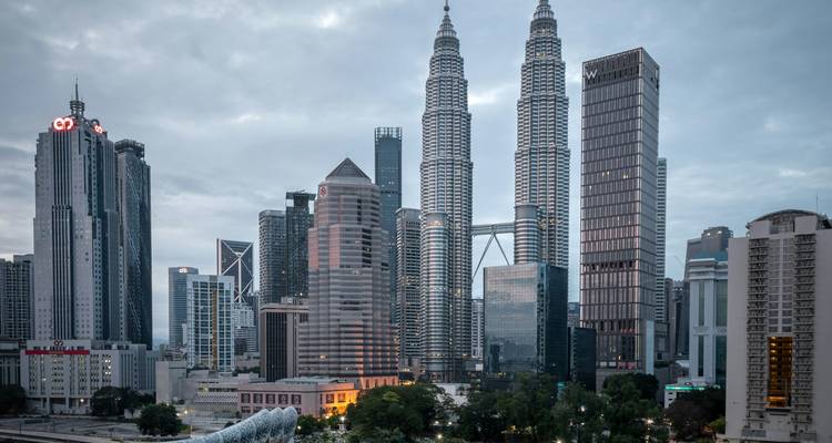 Horizonte de Kuala Lumpur con las Torres Gemelas Petronas elevándose sobre los rascacielos circundantes al anochecer.