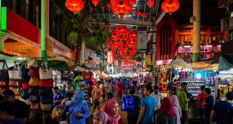 Bazar nocturno colorido lleno de compradores bajo hileras de faroles rojos brillantes