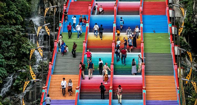 Escalera vibrante pintada de arcoíris de las Cuevas Batu con visitantes subiendo y bajando