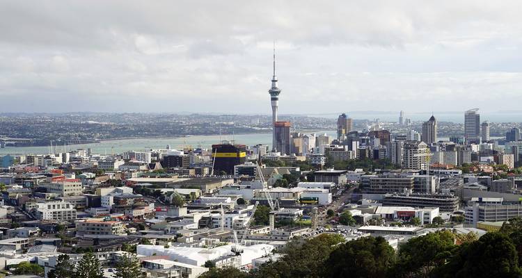 Daytime panorama of Auckland city skyline with the Sky Tower rising above the harbour and suburbs.
