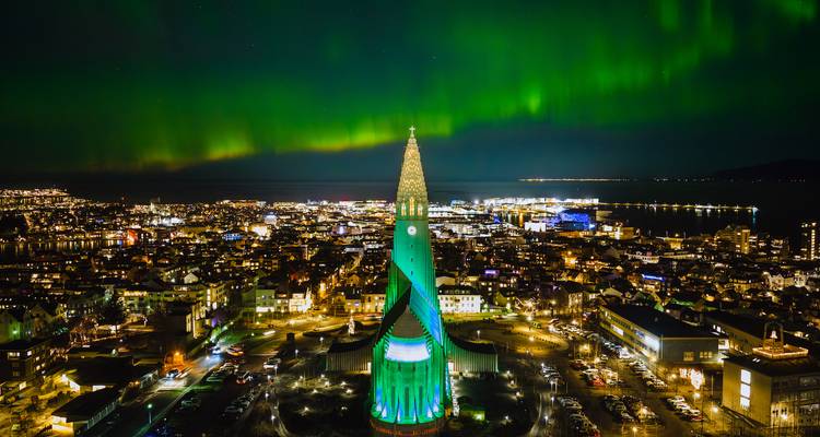 Luchtfoto nachtbeeld van Reykjavik met Hallgrímskirkja kerk die groen gloeit onder het noorderlicht