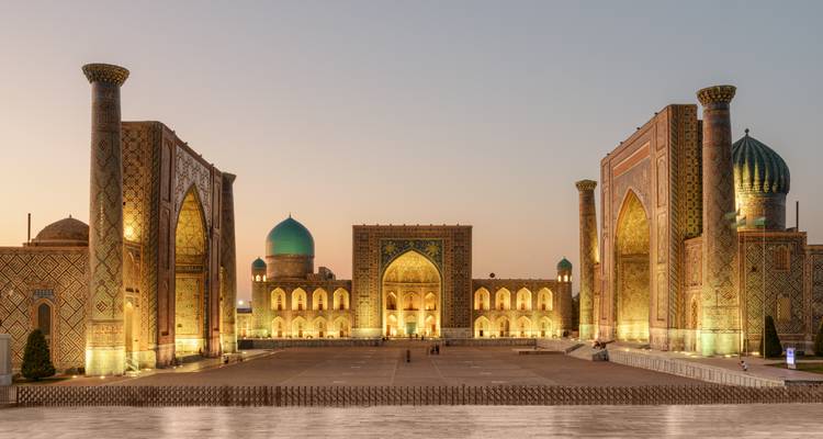 Las tres majestuosas madrasas de la Plaza de Registán brillan suavemente al atardecer en Samarcanda.