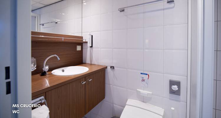 Compacte cruise-schip WC met houten wastafel, ronde gootsteen en witte tegels.