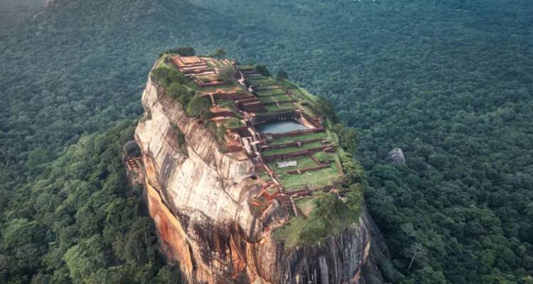 Dramatische Luftaufnahme der Sigiriya-Felsenfestung, die sich über die dichte Dschungellandschaft erhebt.